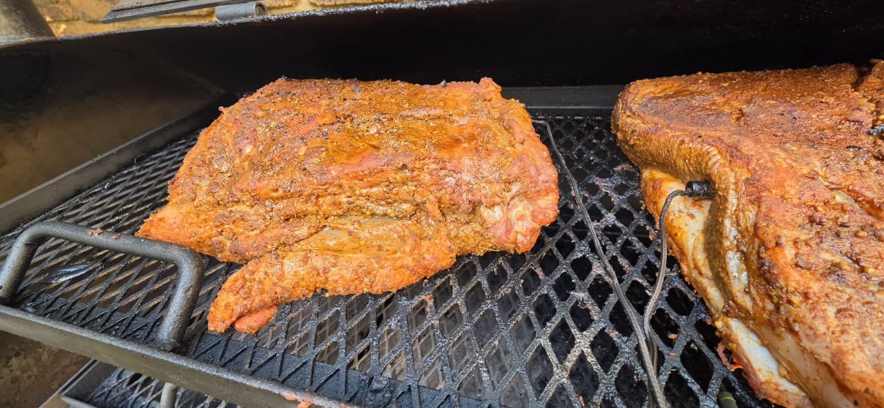 Close-up of spice-crusted brisket on the smoker grid