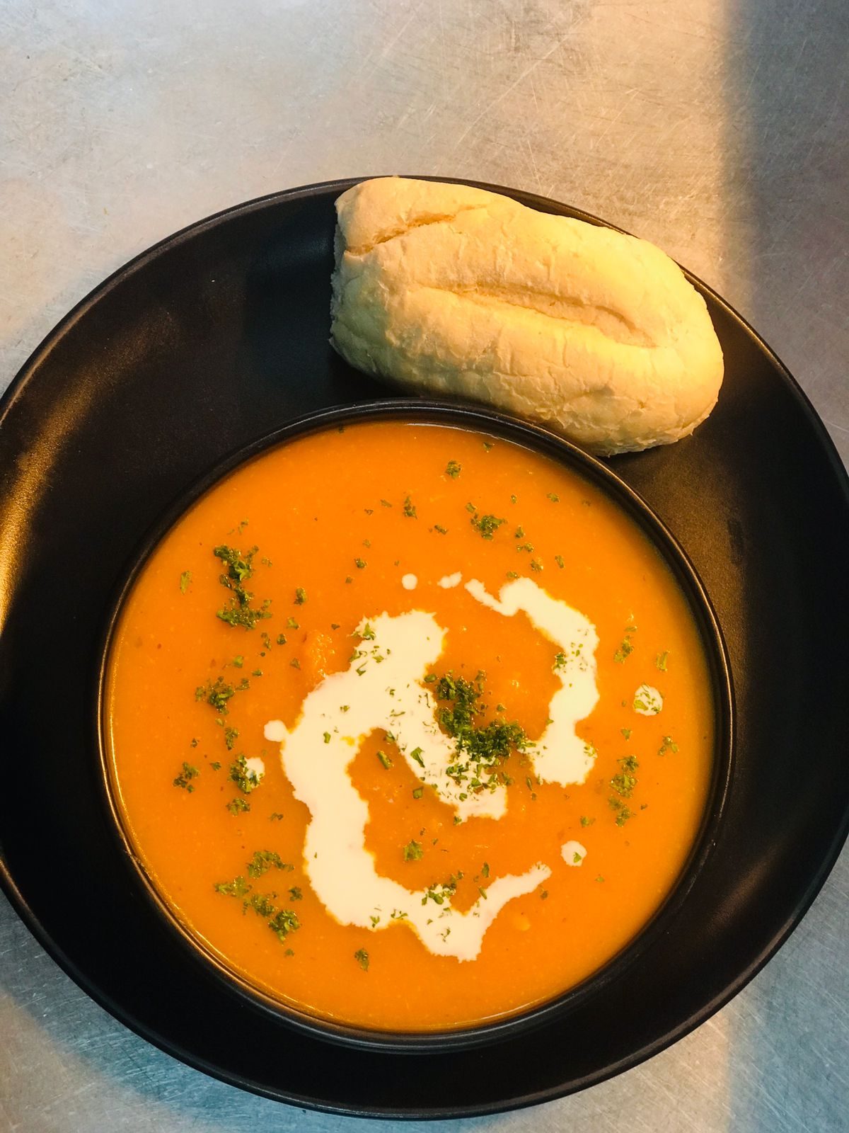 Roasted butternut soup with cream swirl, fresh herbs and a warm roll